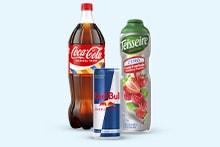 Drie drankproducten: een fles Coca-Cola, een blikje Red Bull en een flesje Teisseire frambozensiroop.