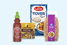 Flessen sriracha saus, Conimex nasi goreng kruidenmix, Lassie Toverrijst en pasta penne rigate naast elkaar opgesteld