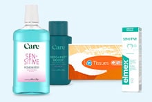 Mondspoeling Care Sensitive, Care Boost Shampoo, een doos tissues en Elmex Sensitive tandpasta naast elkaar op een lichtblauwe achtergrond.