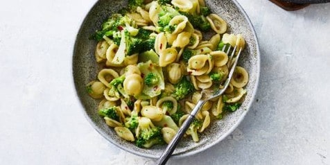 Orecchiette pasta met broccoli en kruiden in een grijze kom met een vork.