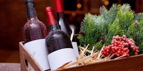 Cadeaumand met flessen wijn en kerstdecoratie.