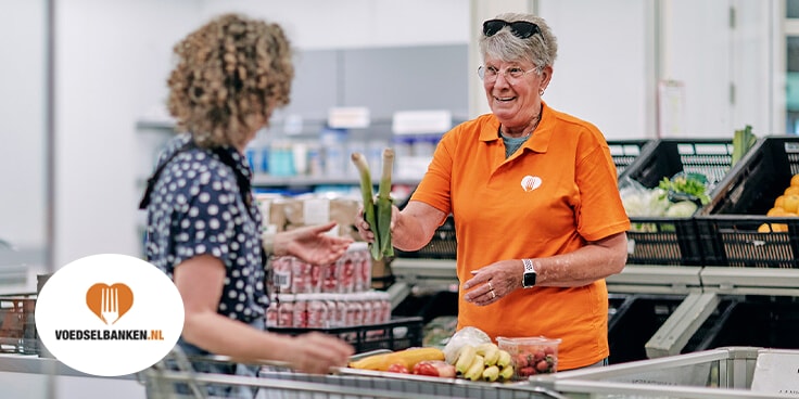 Voedselbank vrijwilliger overhandigt voedsel aan klant in supermarktomgeving.