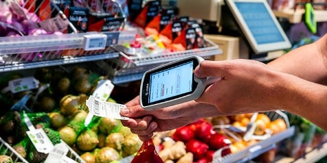 Klanten scannen boodschappen met een handscanner in Albert Heijn supermarkt.