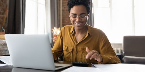 Persoon werkt op een laptop in een thuiskantooromgeving.