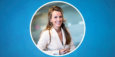 Vrouw in witte jas op een blauwe achtergrond, gezicht geblurd.