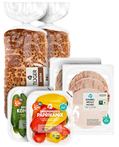 Assortiment van AH producten met volkorenbrood, gesneden kipfilet, komkommers en paprika's