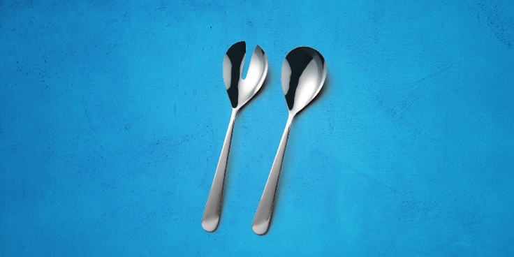 Twee metalen saladebestekken op een blauwe achtergrond.
