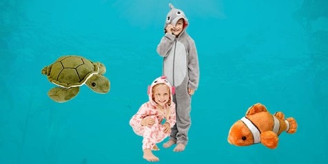 Kinderen in dieren onesies met speelgoed pluchen schildpad, haai en clownvis op een blauwe achtergrond.