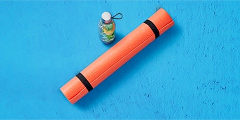 Yoga mat en waterflesje op blauwe achtergrond.