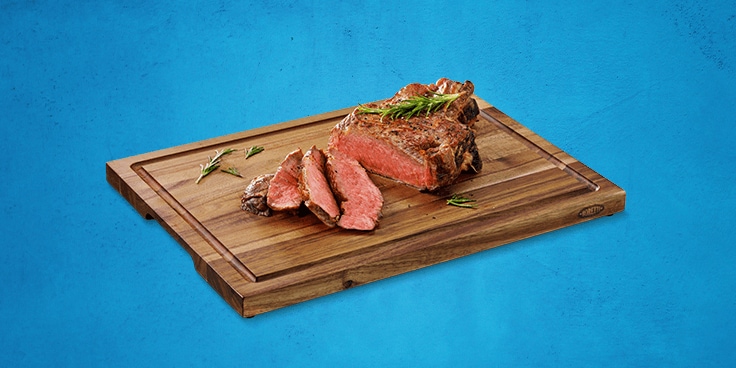 Bereide steak op een houten snijplank met takjes rozemarijn.