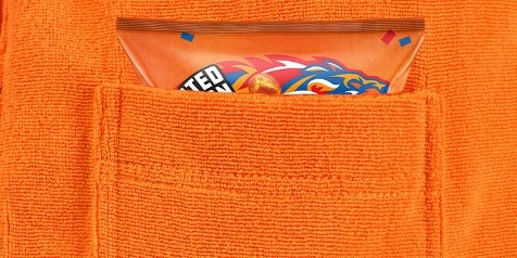 Een zak chips met een opvallend oranje ontwerp, deels zichtbaar in de borstzak van een oranje handdoekstof trui.