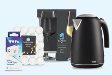 Zwarte Hema waterkoker, set van AH wijnglazen, doos Voya wal chargers en een verpakking witte waxinelichtjes.
