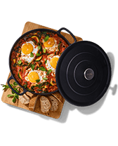 Ovenschotel met gebakken eieren, groenten en brood op een houten plank