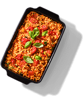 Ovenschotel met tomatensaus en verse basilicum in een zwarte ovenschaal.