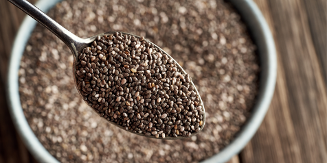 Lepel vol chiazaad boven een kom gevuld met chiazaad.