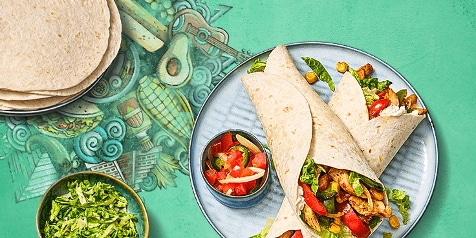 Twee gevulde wraps met kip en groenten, geserveerd met een schaaltje tomatensalsa en gesneden sla.