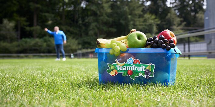 Mand met fruit van Teamfruit op een grasveld.