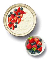 Kom yoghurt met aardbeien en blauwe bessen en een bakje vers fruit.