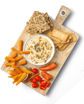 Houten snijplank met hummusdip, cherrytomaatjes, wortelsticks, paprika's en diverse soorten crackers.