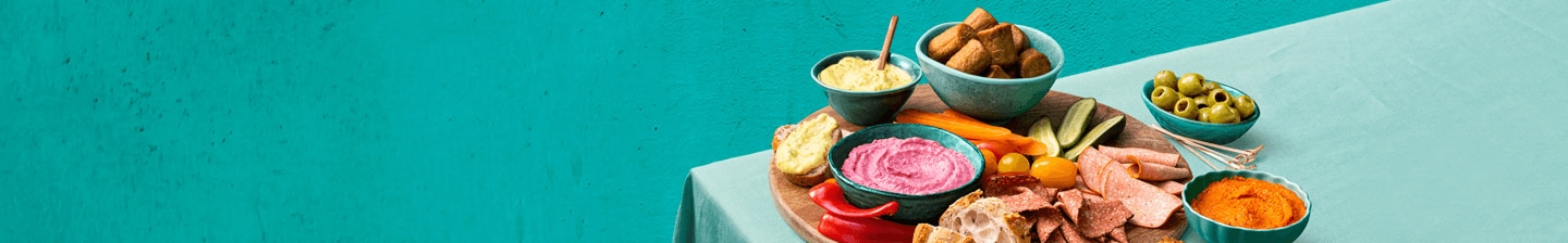 Borrelschotel met diverse dips, groenten en hapjes op een tafel.