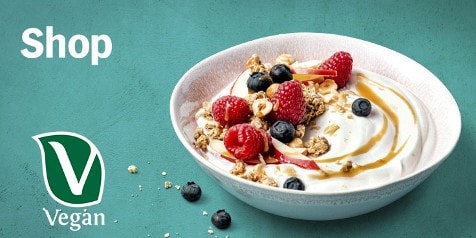 Vegan ontbijtkom met yoghurt, frambozen, blauwe bessen en granola