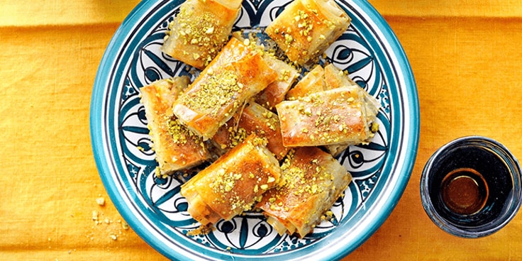 Baklava geserveerd op een decoratief bord met pistachenotensnippers.