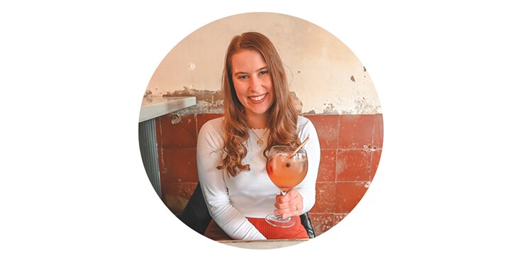 Persoon met een glas vruchtencocktail tegen een achtergrond van een bakstenen muur