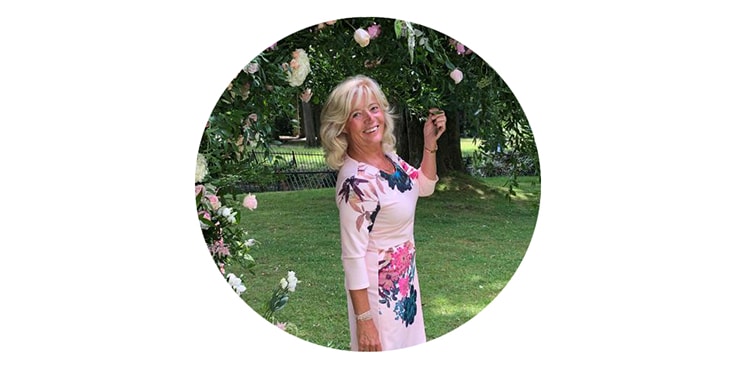 Vrouw in een roze bloemenjurk in een tuinomgeving