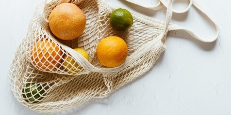Herbruikbare netzak met citrusvruchten, waaronder sinaasappels, citroen en limoen.