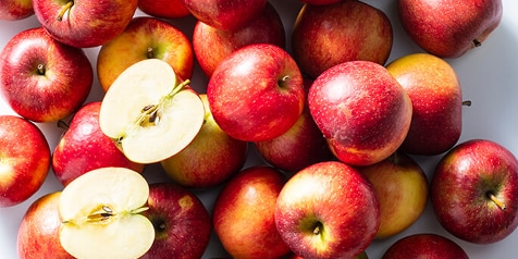 Een groep rode appels, waarvan één doormidden gesneden is.