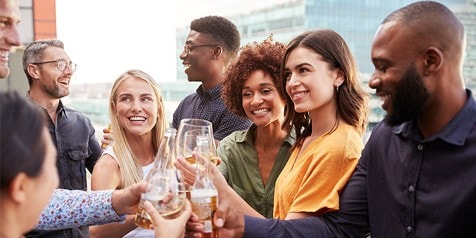 Groep mensen proost met glazen bier en wijn tijdens een borrel op het dakterras