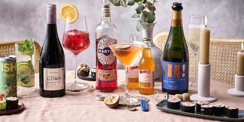 Assortiment van dranken en hapjes op een tafel, inclusief Martini Vibrante en sushi