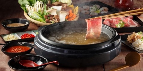 Japans shabu-shabu gerecht met rundvlees en groenten in warme bouillon op tafel.