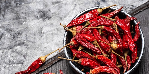 Kom grijze kom met gedroogde rode pepers op een marmeren ondergrond