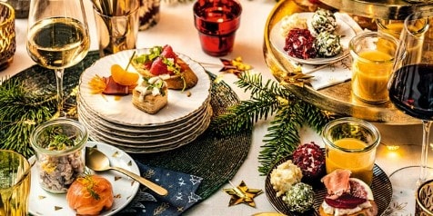 Feestelijke tafelopstelling met diverse hapjes, glazen wijn en kerstdecoraties