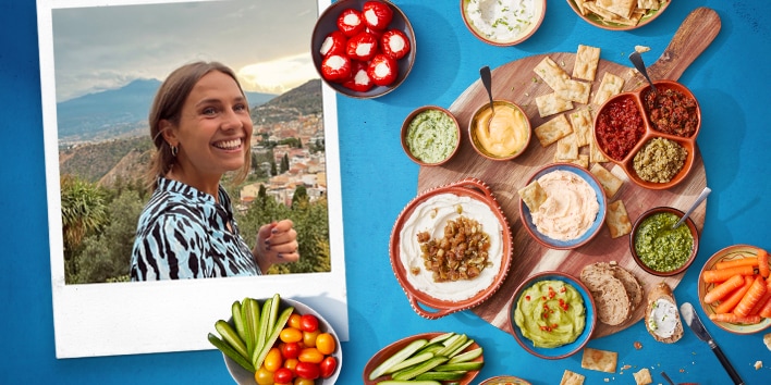 Gezellig borrelplank met diverse dips en groenten, waaronder hummus, guacamole, en gesneden komkommer, met een polaroidfoto op de achtergrond.