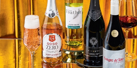 Alcoholvrije wijnen, waaronder GoGo Zero Sparkling Rosé, Free Feather Chardonnay, Viverty Sparkling en Sangre de Toro, gepresenteerd op een gouden achtergrond.