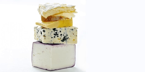 Stapeltje kaas met verschillende soorten kaas, inclusief blauwe kaas, geitenkaas en brie.