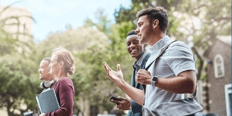 Groep jonge mensen buiten in gesprek, met notitieboek en mobiel, op een zonnige dag