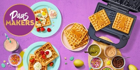 Paasmaker set-up met wafels, vruchten en een wafelijzer op een paarse achtergrond