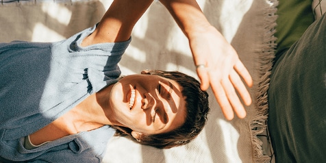 Persoon ontspannen liggend op een bank met zonnestralen die binnenvallen.