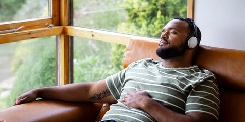 Man met koptelefoon ontspant op een leren stoel.