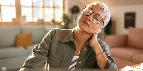 Een vrouw met haar ogen dicht met hand in haar nek