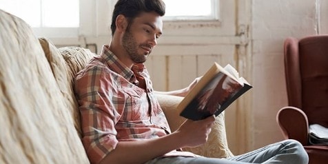 Man leest een boek op een bank in een ontspannen omgeving.