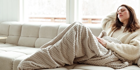 Persoon ontspannen op een bank met een warme deken.
