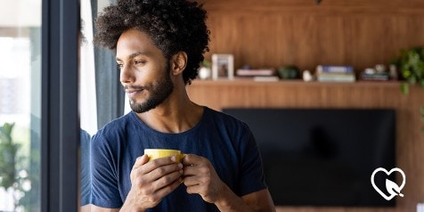 Persoon met krullend haar houdt een gele kop vast voor een raam.