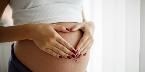 Zwangere vrouw houdt haar buik vast met beide handen