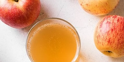 Verse appels en een glas appelsap op een witte achtergrond.