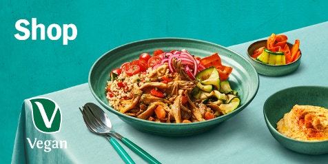 Vegan lunchgerecht met couscous, cherrytomaten, gegrilde groenten en hummus.