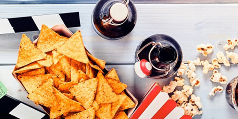 Nacho chips, popcorn en frisdrank op een tafel met een filmscene.